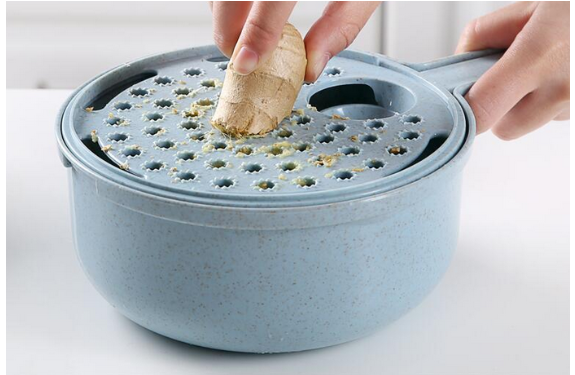 Person squeezing a cork into a blue steamer pot with a perforated lid, releasing grated pieces.